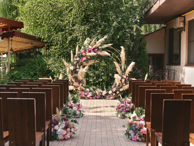 TrueWedding – Celkový pohled na venkovní obřadní prostor s připravenými židlemi a květinovou slavobránou