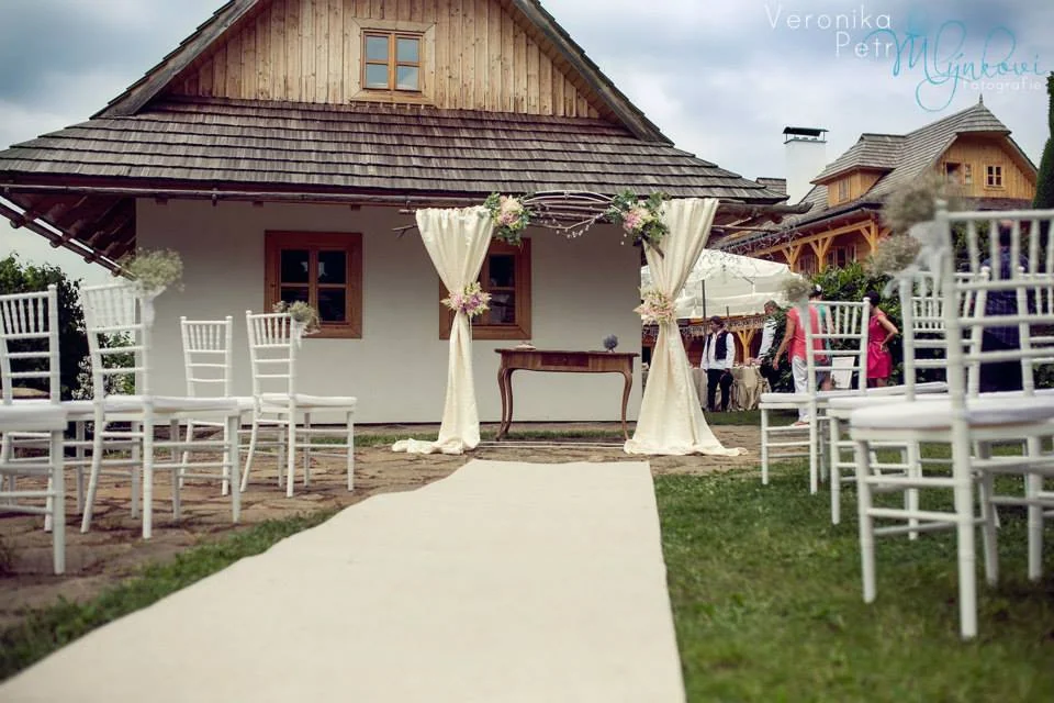 With Love – Celkový venkovní obřadní prostor s bílými židlemi a slavobránou