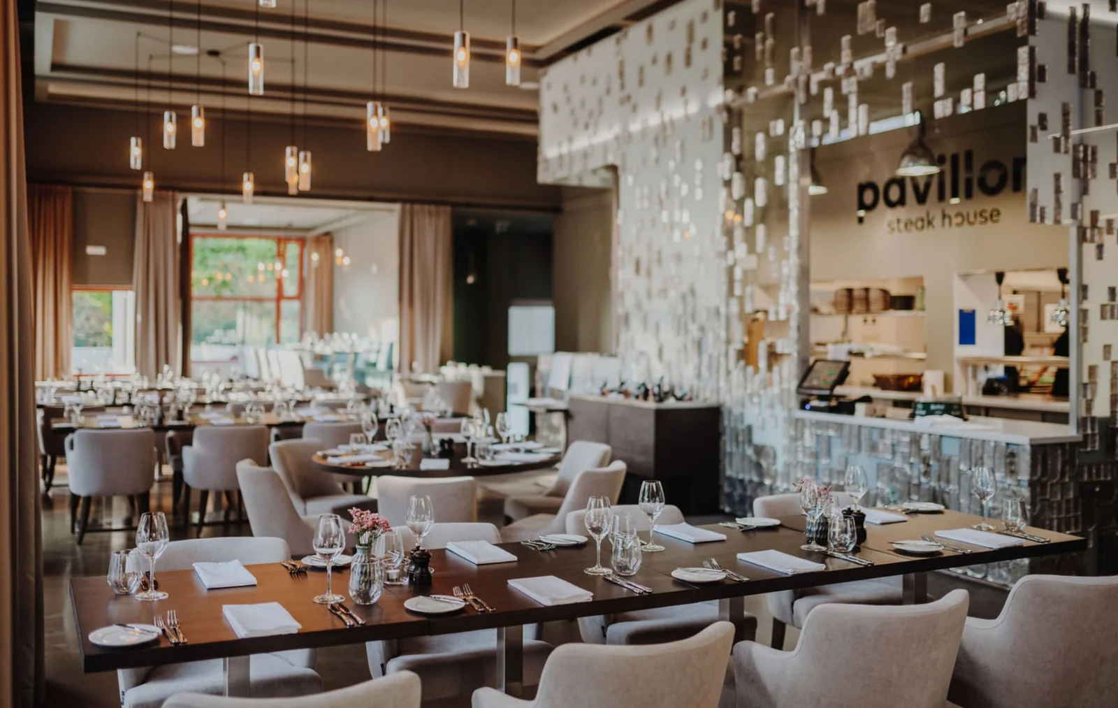 Pavillon Steak House – Široký pohled na interiér restaurace s prostřenými stoly.